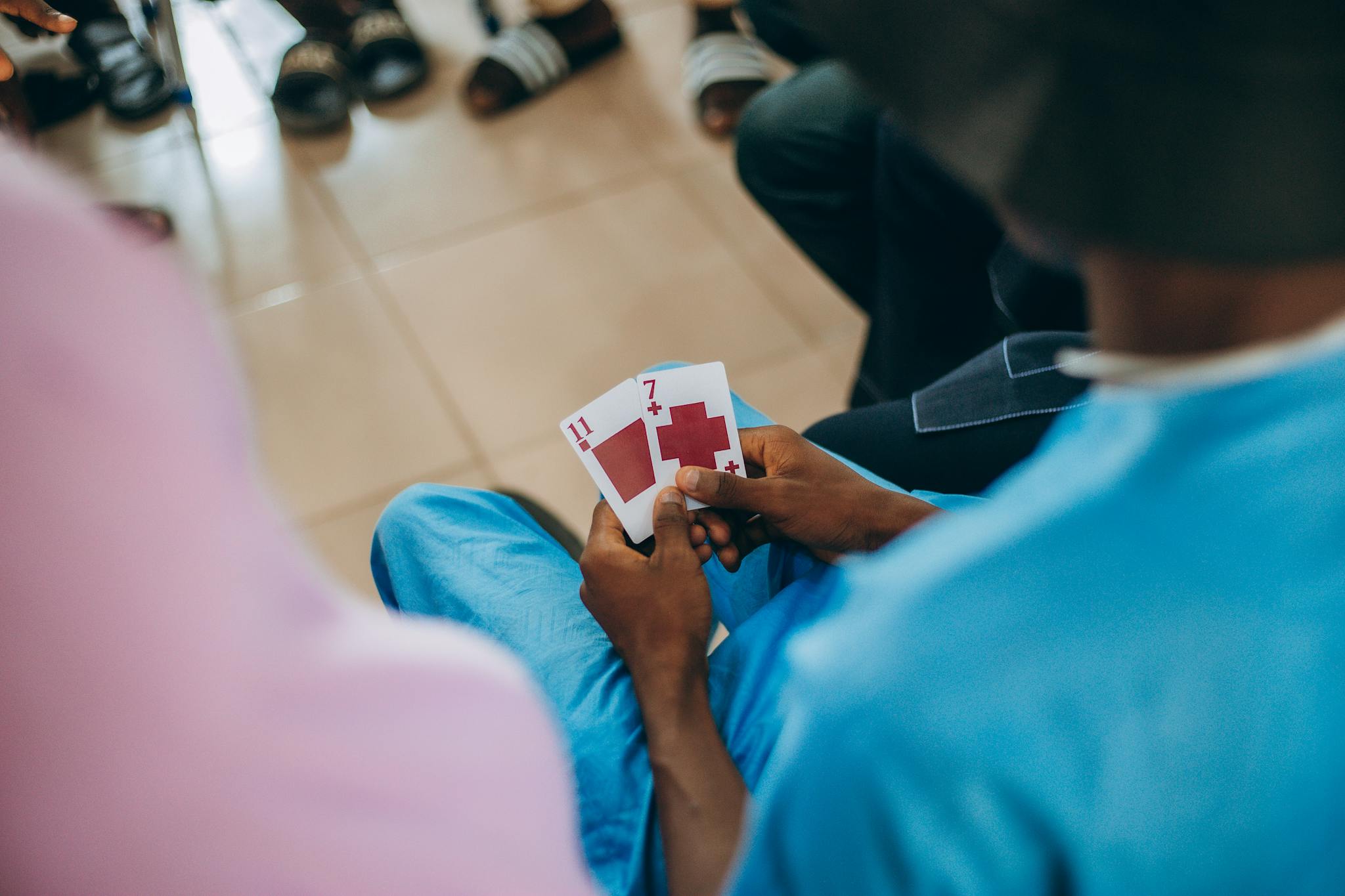 A man holds playing cards, focusing on a game with friends in a casual indoor setting.